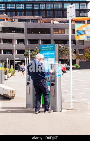Senior man using Pay and Display parking meter in Wellington New Zealand. Model release available for senior man. Stock Photo