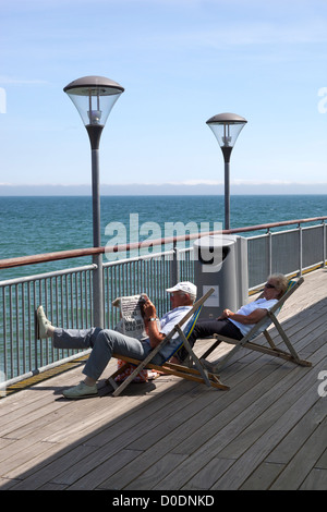 Couple relaxing in deckchairs on Boscombe Pier Stock Photo