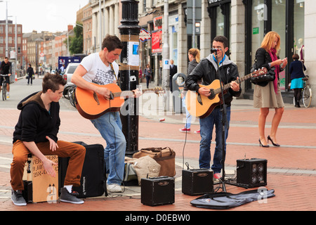 Typical street scene with three Irish musicians playing guitars busking in city centre on Grafton Street Dublin Ireland Eire Stock Photo