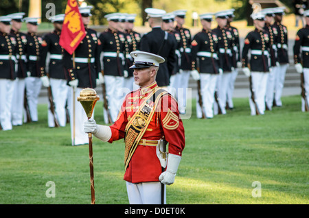 ARLINGTON, Virginia, United States — Marines perform during the Marine Corps Sunset Parade at the Marine Corps War Memorial, also known as the Iwo Jima Memorial, in Arlington, Virginia. The Sunset Parade, featuring the Silent Drill Platoon and the Commandant's Own Drum and Bugle Corps, takes place on Tuesday evenings during the summer months. The iconic memorial, depicting the flag raising on Iwo Jima, serves as a dramatic backdrop for this longstanding military tradition. Stock Photo