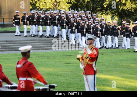 ARLINGTON, Virginia, United States — Marines perform during the Marine Corps Sunset Parade at the Marine Corps War Memorial, also known as the Iwo Jima Memorial, in Arlington, Virginia. The Sunset Parade, featuring the Silent Drill Platoon and the Commandant's Own Drum and Bugle Corps, takes place on Tuesday evenings during the summer months. The iconic memorial, depicting the flag raising on Iwo Jima, serves as a dramatic backdrop for this longstanding military tradition. Stock Photo