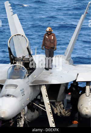 A flight deck captain does checks on an F/A-18E Super Hornet on the flight deck of the aircraft carrier USS Nimitz November 11, 2012 in the Pacific Ocean. Stock Photo