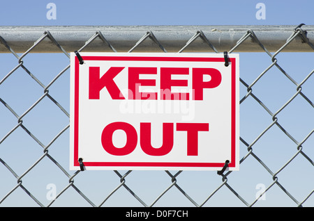 red and white keep out sign on a chain link fence Stock Photo