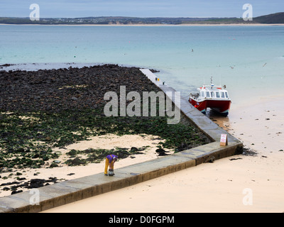 Low tide on the beach at St Ives, Cornwall. A fisherman works on his twin hulled boat on the jetty outside the main harbour. Stock Photo