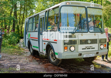 Bus on forest road after fording. Stock Photo