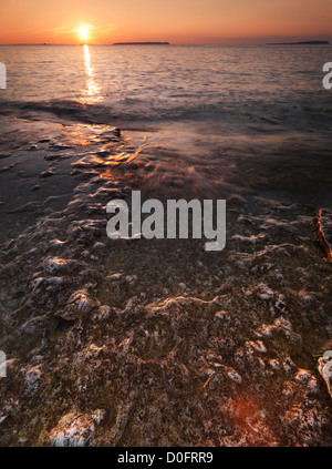 Sunset scenery of waves hitting rocks on a shore of Georgian Bay. Sunset landscape nature scenery in golden colors Canada Stock Photo