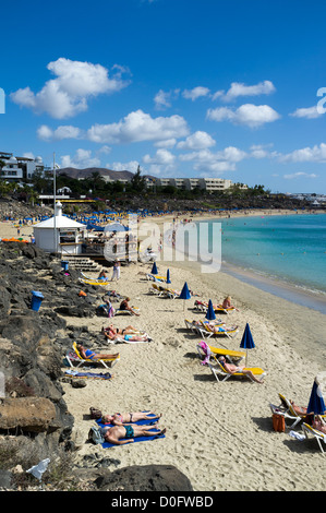 dh Playa Dorada Beach PLAYA BLANCA LANZAROTE Sunbathers relaxing white sandy holiday resort beach canary islands people holidays in sun Stock Photo