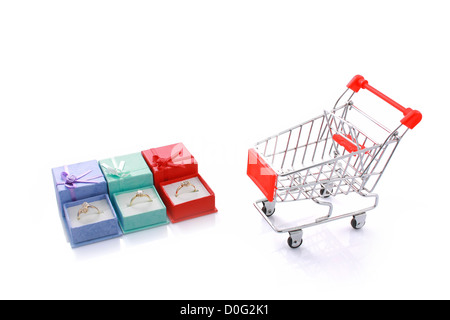 Three rings in gift boxes with empty shopping cart isolated on white with copyspace Stock Photo