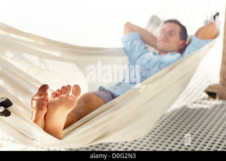 Young barefooted vacationer enjoys a nap in a hammock Stock Photo