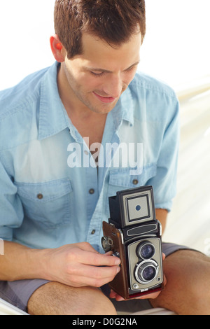 Young male on vacation, winds up an antique camera Stock Photo