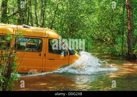 Yellow minibus fording small river. Stock Photo