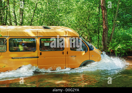 Yellow minibus fording small river. Stock Photo