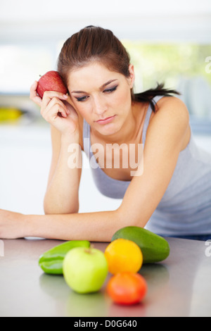 An attractive young woman deciding staring at the fruit and vegatables in front of her Stock Photo