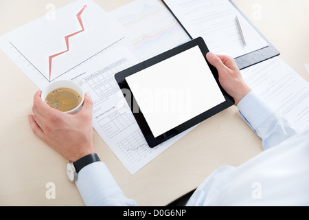Businessman at workplace drinking coffee and looking at the blank digital computer. Stock Photo