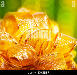 Picture of golden ribbon bow border, yellow Christmastime decoration isolated on glowing green background, birthday present Stock Photo