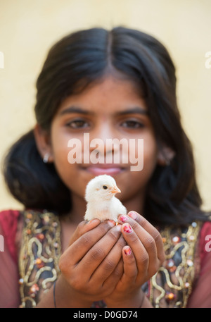 Young Indian girl holding a chick in the palm of her hands. India Stock Photo