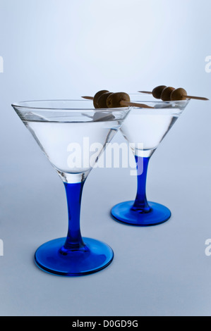 Two stylish Martini glasses on gray white background. Two Martini's with olives Stock Photo