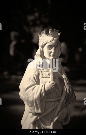 Stone statue of female figure holding cross in cemetery UK Stock Photo