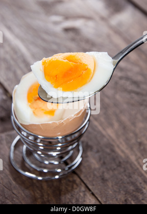 Spoon with breakfast egg on wooden background Stock Photo