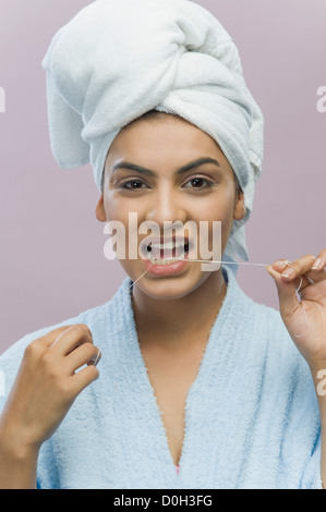 Portrait of a young woman flossing her teeth Stock Photo