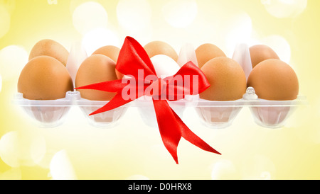 White egg wrapped around with red ribbon and pack with yelolow lights in the background Stock Photo