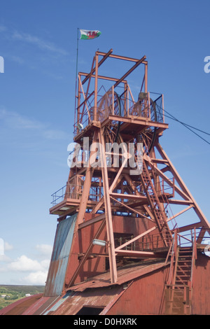 Winding gear at Big Pit, Blaenavon, Wales, UK. Welsh flag flying against clear blue sky. Stock Photo