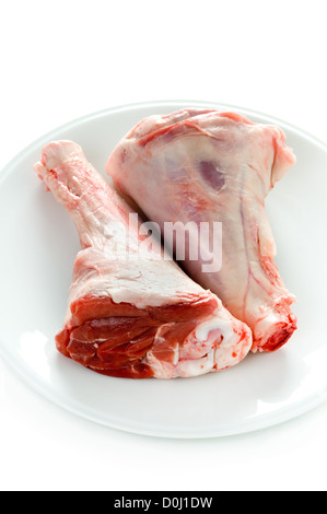 lamb shank two raw uncooked on a white plate Stock Photo