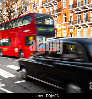 A red London bus and Black Cab Taxi approach the famous Abbey Road pedestrian crossing made famous by the cover of the Beatles a Stock Photo