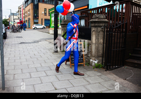 A man dressed in a union jack costume carries balloons down Whiteladies Road in Bristol. Stock Photo