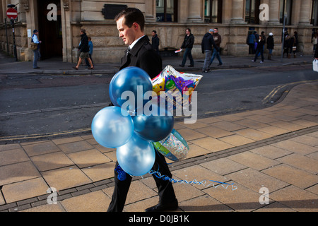 A man walking with some balloons in Cheltenham. Stock Photo