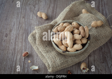 Bunch of peanuts in a bowl on wooden table Stock Photo