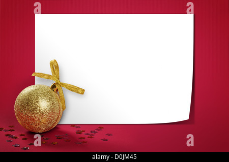 Christmas gold glitter bauble over red background with blank paper. Stock Photo