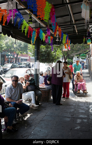 El Jarocho Coffee House clientele sit on benches along pavement enjoying their brew in Coyoacan in Mexico City DF Stock Photo