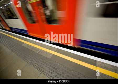 A tube rushes past a platform on the London Underground system. Stock Photo