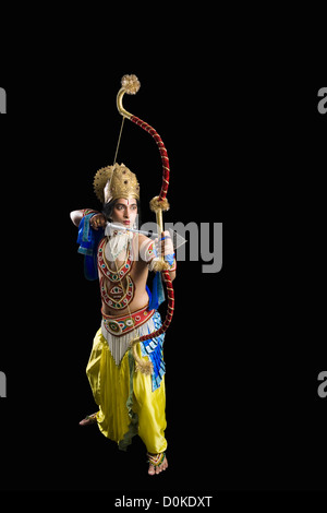 Stage artist dressed-up as Rama and holding a bow and arrow Stock Photo