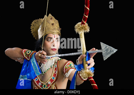 Stage artist dressed-up as Rama and holding a bow and arrow Stock Photo