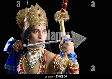 Stage artist dressed-up as Rama and holding a bow and arrow Stock Photo