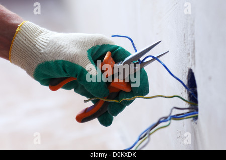 worker puts the wires in the wall Stock Photo