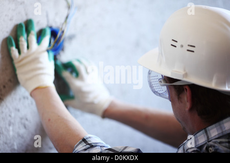 worker puts the wires in the wall Stock Photo