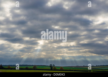 Evening sky over farmland with sun rays breaking through clouds Stock Photo