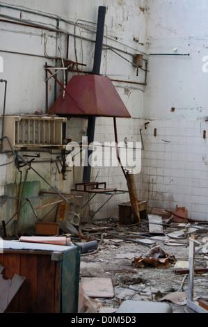 Discarded equipment and debris in abandoned factory decayed industrial interior. Stock Photo