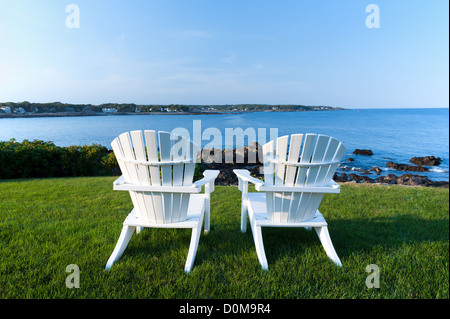 Two white Adirondack chairs on a lawn overlooking the Atlantic Ocean in York Beach, Maine, USA. Stock Photo
