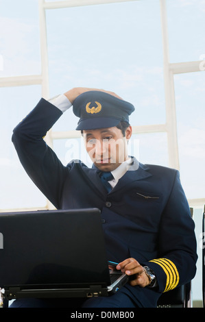 Pilot using a laptop at an airport and looking confused Stock Photo