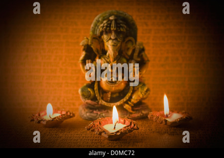 Diwali oil lamps in front of an idol of Lord Ganesha Stock Photo