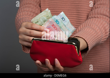 Chinese woman holding Yuan banknotes the official currency of mainland China with a red purse Stock Photo