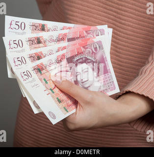 Woman's hand holding fifty pound notes UK British currency Stock Photo