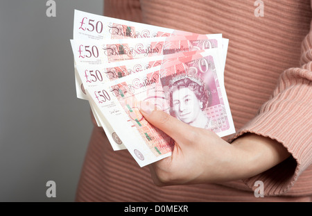 Woman's hand holding fifty pound notes UK British currency Stock Photo