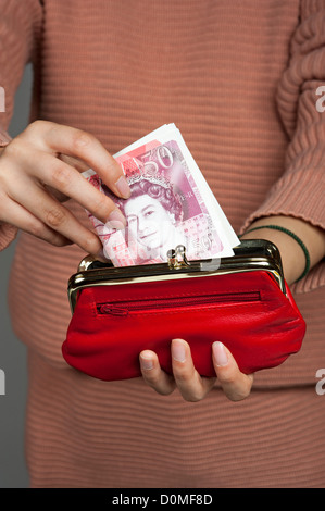 Woman's hand with fifty pound banknotes and a red purse British Sterling Stock Photo
