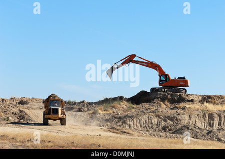 Daewoo excavator working in a construction site loading an articulated Volvo dumper truck Stock Photo