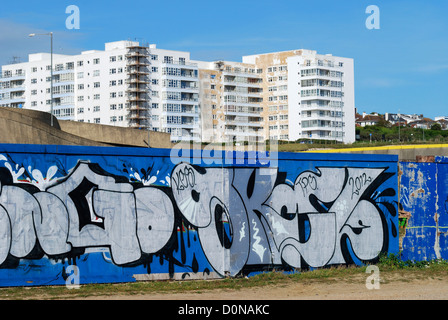 Graffiti on wall near Marina with block of flats being repainted in background. Brighton. East Sussex. England Stock Photo